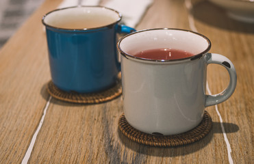 Blue and white vintage metal cups with tea on a wooden table 