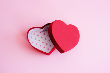 An open red heart-shaped gift box for a loved one. Happy Valentine's Day. Love. The red heart-shaped gift box lies open on a pink background.