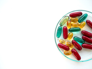 Multivitamin nutrition capsules including omega 3 in fish oil, amino acid and zinc for healthcare in clear watch glass of science laboratory with left copy space on isolated white background