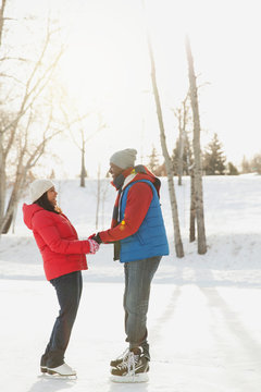 Profile shot of couple holding hands on ice skates