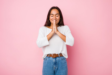 Young mixed race indian woman holding hands in pray near mouth, feels confident.