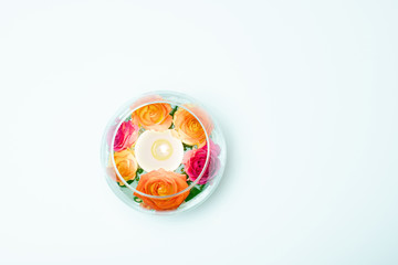 Top view of beautiful spray roses with burning candle in vase on white background 