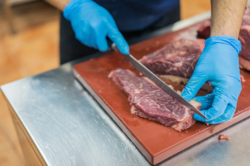 chef's hand cutting a piece of meat on a table in a restaurant kitchen