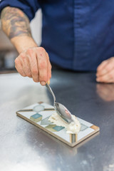 chef's hand placing food on a plate in a restaurant kitchen