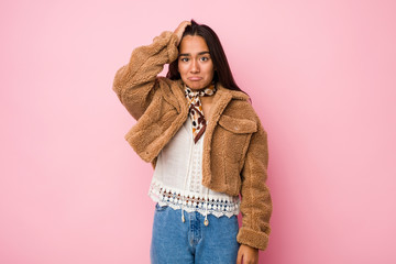 Young mixed race indian woman wearing a short sheepskin coatbeing shocked, she has remembered...