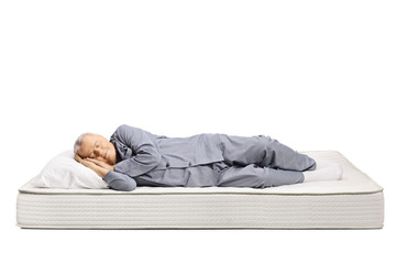 Elderly man in pajamas sleeping on a bed mattress