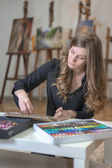 Female artist painting picture using colored pencils sitting at her stylish workshop