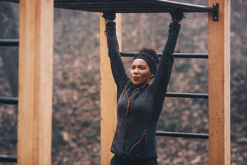 Fototapeta premium A young woman doing exercises in an outdoor workout equipment.