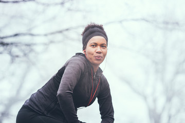A woman warming up for exercise on a misty morning in nature.
