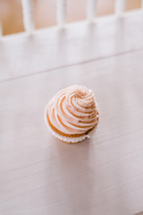 Cupcake with pink icing and pearl sprinkles on white bench