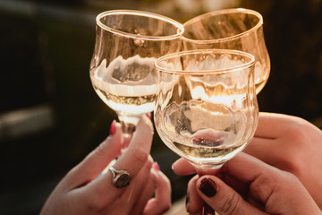 Close up glass with drink make cin cin to celebrate holidays - Group of friends having beautiful time with wine on sunset - Millennial boys and girls having fun with luxury champagne