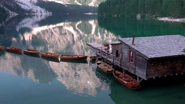 Wooden boats and house on summer morning at Lago di Braies, Italy