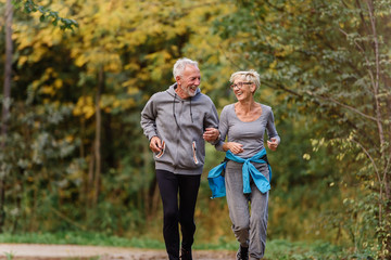 Cheerful active senior couple jogging in the park. Exercise together to stop aging.