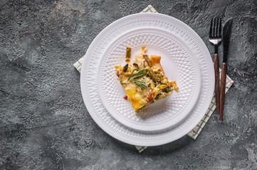 Baked vegetable lasagna with green beans and cheese on a white plate. Delicious vegetarian food. Top view. Copy space