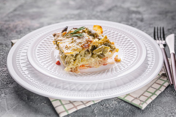 Close up baked vegetable lasagna with green beans and cheese on a white plate. Delicious vegetarian food.
