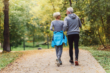 Cheerful active senior couple jogging in the park. Exercise together to stop aging.