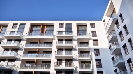 Modern multi story building being lit by the setting sun at afternoon. New apartment house residential building outdoor concept.