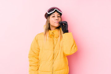 Young caucasian woman wearing a ski clothes in a pink background with fingers on lips keeping a secret.