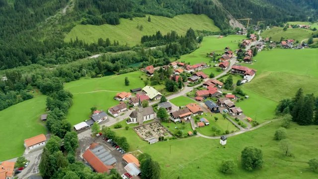 Scenic Aerial View of Mountain Village in Alpine Countryside. Agriculture and Ecotourism in Bavaria, Germany. 4K Drone Fly over Shot