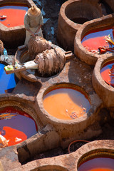 Worker scrapes leather with fast movements in a traditional tannery in the city Fes, Morocco