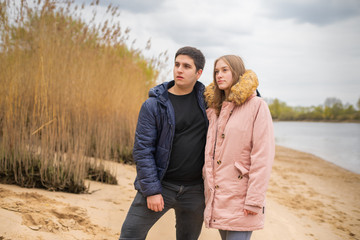 young couple stands on a beach and looks in a direction