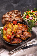 Roasted chicken wings with baked potatoes on rustic background