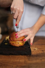 Girl slicing burger on chopping board hands