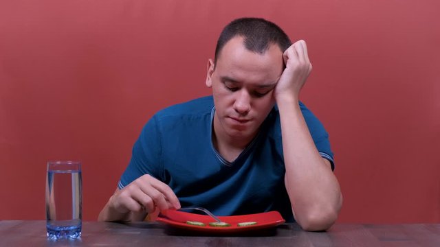 young man feeling sad and bored with diet not wanting to eat vegetables or healthy food in Dieting Eating Disorders and weight loss concept.