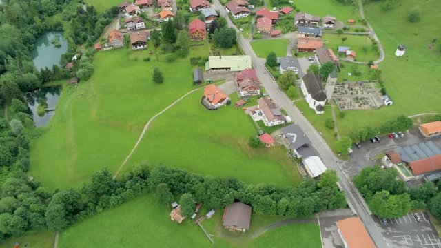 Close up Aerial View of Village in Alps Mountains. Alpine Countryside with Lakes, Forest and Car road. Agriculture and Ecotourism in Hinterstein, Germany, Europe. 4K Drone Fly over Shot