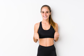 Fototapeta na wymiar Young caucasian fitness woman posing in a white background points down with fingers, positive feeling.
