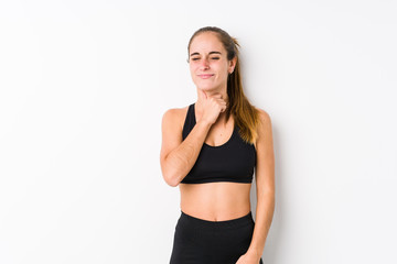 Young caucasian fitness woman posing in a white background suffers pain in throat due a virus or infection.