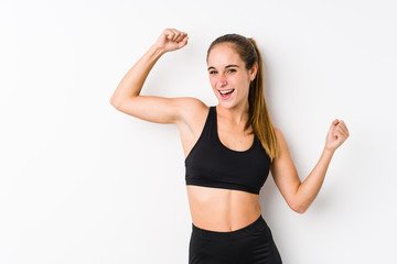 Fototapeta na wymiar Young caucasian fitness woman posing in a white background celebrating a special day, jumps and raise arms with energy.