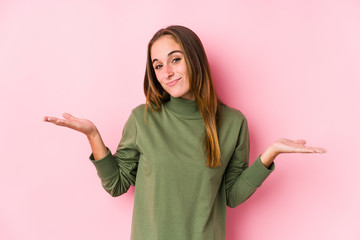 Young caucasian woman posing isolated  doubting and shrugging shoulders in questioning gesture.