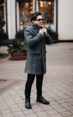 man in the evening city in a gray coat in cold weather walks around the city on holidays on a date.