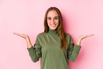 Young caucasian woman posing isolated  makes scale with arms, feels happy and confident.