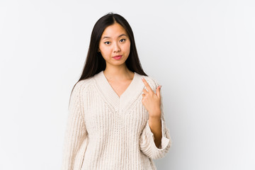 Young chinese woman isolated pointing with finger at you as if inviting come closer.