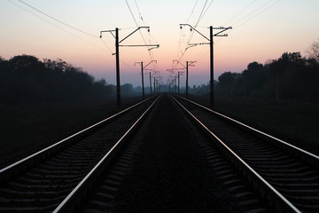 Fototapeta na wymiar Two tracks of railroad tracks receding towards sunset.