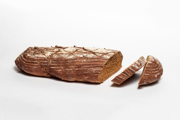 Sliced loaf of black rye bread with cuts from a knife on top of it and sprinkled with white flour isolated on a white background. Healthy eating concept.