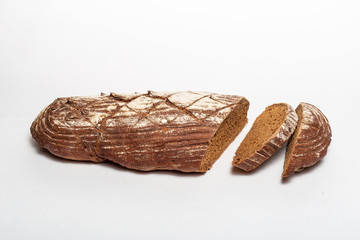 Sliced loaf of black rye bread with cuts from a knife on top of it and sprinkled with white flour isolated on a white background. Healthy eating concept.