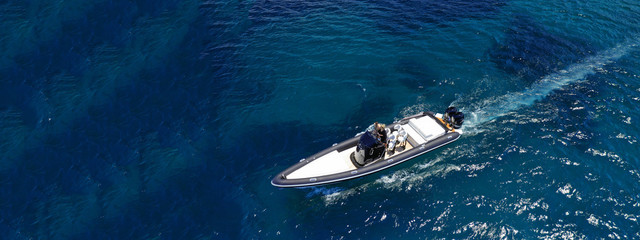 Aerial drone ultra wide top down photo of luxury rib inflatable with wooden deck cruising in deep blue open ocean sea