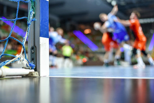 Detail of handball goal post with net and handball match in the background.