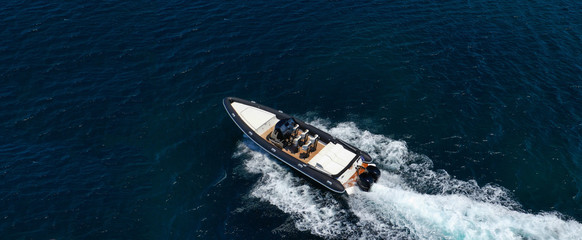 Aerial drone ultra wide top down photo of luxury rib inflatable with wooden deck cruising in deep blue open ocean sea