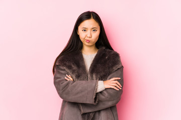 Fototapeta premium Young chinese woman wearing a coat isolated frowning face in displeasure, keeps arms folded.