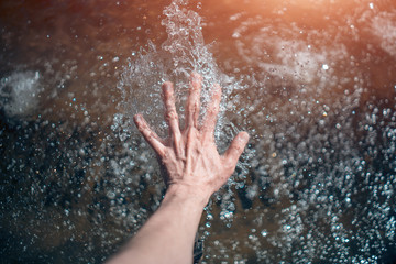 male hand touches the clear water of the river