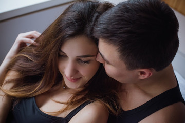 Close-up portrait of a couple in love lying on a bed at home, tenderly hugging each other and...