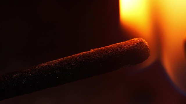 Close up macro footage of an incense stick being lit and burning