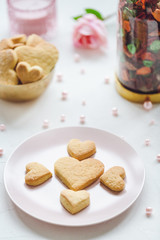 Heart shaped butter cookies on a pink plate, rose and candle on the table. Valentines Day concept