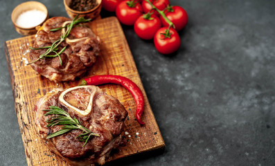 two steaks on the grill, with tomatoes and spices on a stone background, with copy space for your text. dinner concept for two