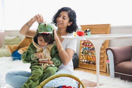 Mother sewing dragon costume for son