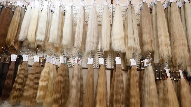 Long fake hair on a bench in a store. Hair Extension Salon